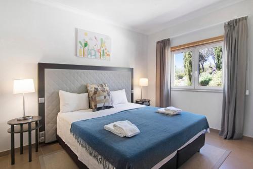 Mexilhoeira GrandeV2 Vale da Ribeira的一间卧室配有一张带蓝色床单的床和一扇窗户。