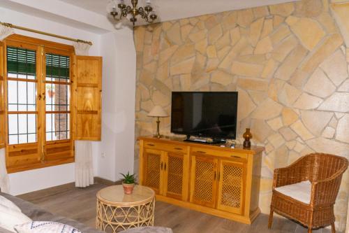 普里埃格·德·科尔多巴La Tesela的一间客厅,在石墙上配有电视
