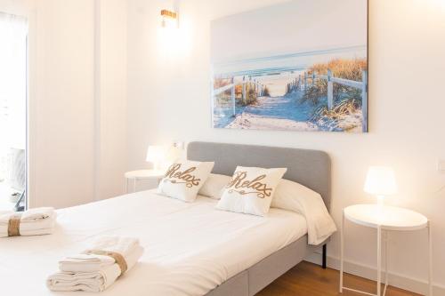 卡耐特蒂贝兰格Global Properties, Moderno apartamento en Canet al Mar的卧室配有一张白色床,墙上挂有绘画作品