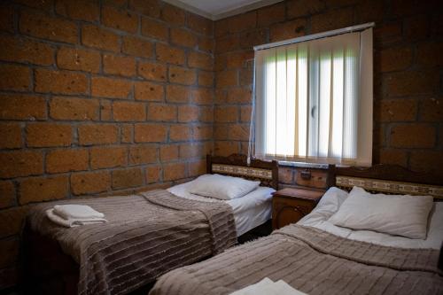 NamazaluNoravank L-and-L的一间卧室设有两张床和砖墙