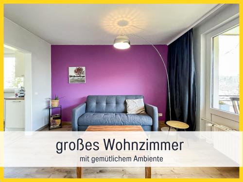 巴特萨克萨HaFe Ferienwohnung Bad Sachsa - waldnah, hundefreundlich, Smart Home Ausstattung的客厅配有蓝色沙发和紫色墙壁