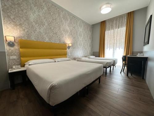 罗马维吉尔酒店的客房设有3张床和黄色床头板