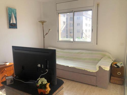卡拉费尔Apartamento a 20 metros de la playa的一间卧室设有一张床、一台电视和一个窗口。