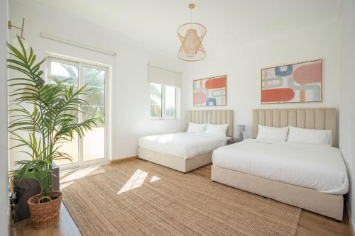 迪拜Jumeirah Islands Private Pool Villa的一间卧室设有两张床和盆栽植物