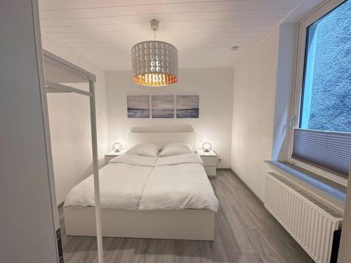 赫恩Möblierte EG- Wohnung zentral in Herne mit Parkplatz,WLAN und Netflix的白色卧室配有一张床和一个吊灯