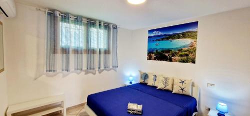 奥尔比亚La casa al mare, Pittulongu的卧室配有蓝色的床和墙上的绘画作品