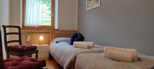 卡瓦莱塞Ai Grisi的一间卧室设有两张床、一把椅子和一个窗户。