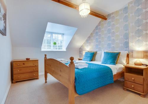 雷文斯卡Smugglers Cove Cottage的一间卧室配有一张带蓝色床单的床和一扇窗户。