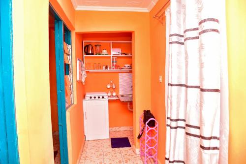 埃尔多雷特CasaAloha Homes- Cozy 1Bdr - Along Eldoret-Kisumu Highway - Near the Edge Bar and Restaurant的一个带橙色墙壁的小走廊和厨房
