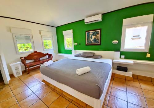 AcajutlaLas Veraneras Villas & Resort的一间卧室设有绿色的墙壁、一张床和椅子