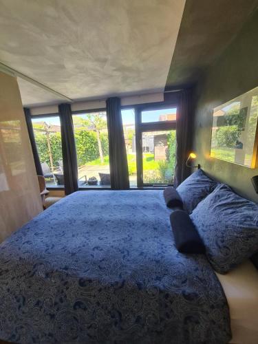 阿森Bed & Breakfast 28 appartement met ruime tuin en gratis prive parkeren ideaal voor gezinnen的一间卧室设有一张大蓝色的床和窗户。