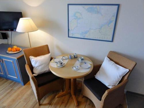 奥斯赛拜-屈隆斯博恩Yachthafenresidenz-Wohnung-8205-853的小桌子,带两把椅子,桌子,盘子和杯子