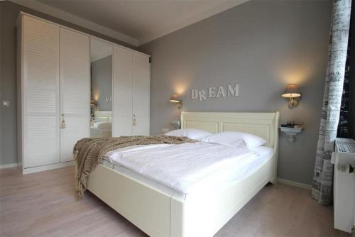 奥斯赛拜-屈隆斯博恩Residenz-Ostseewind-Wohnung-15-9732的卧室内的一张白色床,墙上有标志