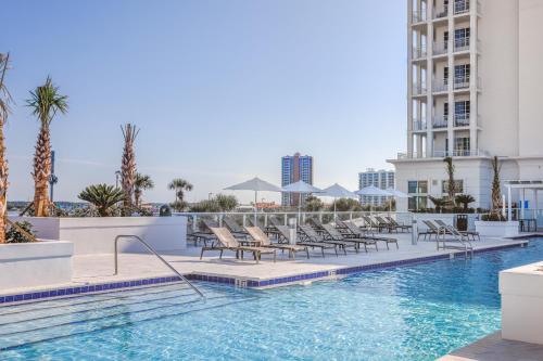 彭萨科拉海滩The Pensacola Beach Resort的一座游泳池,里面摆放着椅子和棕榈树