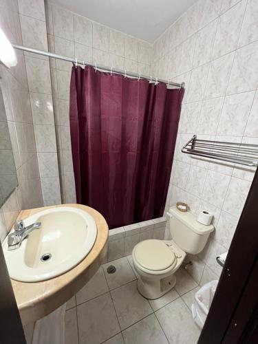 瓜亚基尔里佐酒店的浴室设有卫生间水槽和紫色的浴帘