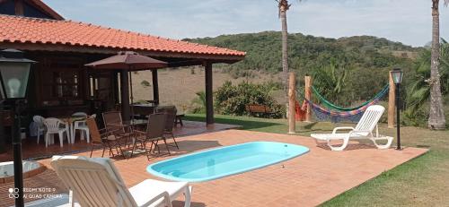 陶巴特chale da montanha的一个带游泳池、椅子和房子的庭院