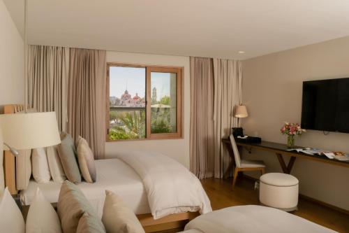 普埃布拉Cartesiano Boutique & Wellness Hotel的一间卧室配有一张床、一张书桌和一个窗户。