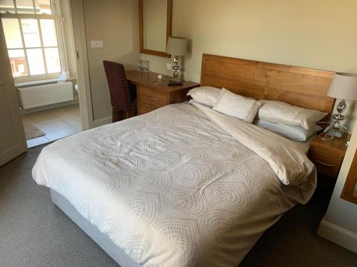 Teach MunnaCuckoos Corner的卧室配有一张白色大床和木制床头板