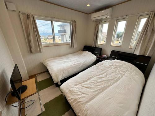 KanayamaSHIRAHAMA condominium D-157的小型客房设有2张床和窗户。