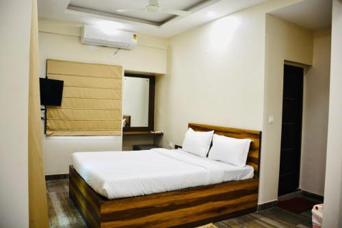 加尔各答Hotel Royal Residency的一间卧室配有带白色床单和枕头的床。