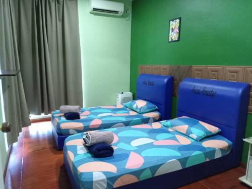 仙本那Awani homestay的带绿色墙壁的客房内的三张床
