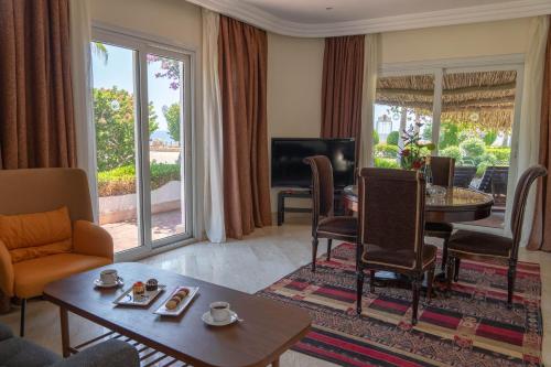 沙姆沙伊赫Sharm Club Beach Resort的客厅配有桌椅和电视。
