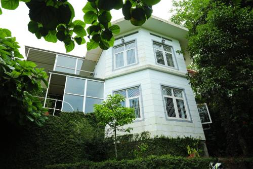 马迪凯里Copperhill- A Luxury Homestay的白色的房子,设有窗户和灌木丛