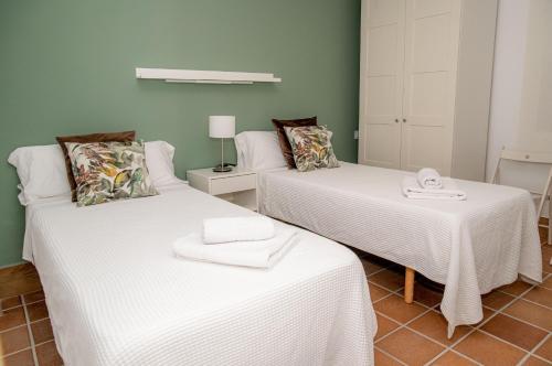阿尔哈拉克Apartamentos Casa Tuli A, ALJARAQUE的一间设有两张带白色床单的床的房间