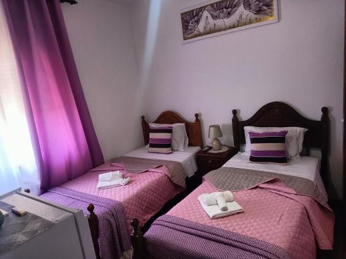 圣地亚哥-杜卡森Alojamento Local Largo da Igreja的配有粉红色和紫色床单的客房内的两张床