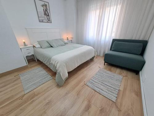 萨龙Apartamento de 120m2 al lado de Cabarceno的一间卧室配有一张床和一把绿色椅子