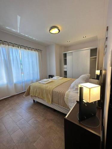 里瓦达维亚海军准将城Estepa Apart 1B calidad y confort的一间卧室配有一张床和一张带台灯的桌子