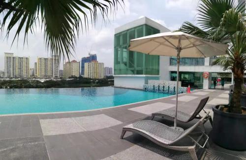吉隆坡Setapak @ Zeta Suite的一座带两把椅子和一把遮阳伞的游泳池以及一座建筑