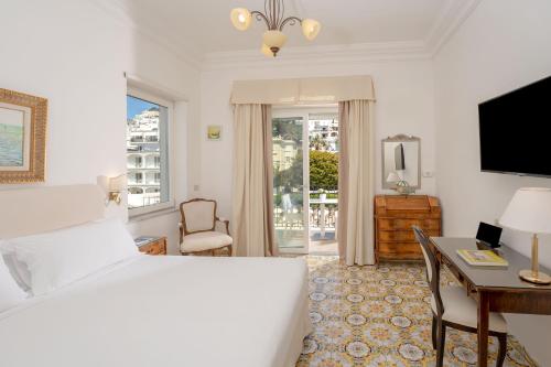 卡普里塞莱尼酒店的一间卧室配有一张床、一张书桌和一台电视