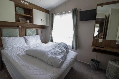斯凯格内斯Great Caravan With Decking Southview Holiday Park In Skegness Ref 33002v的卧室配有白色的床和大窗户