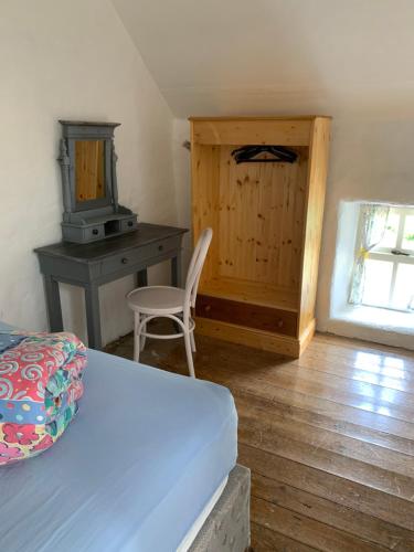 ArdeaWestland Traditional Cottage dated 1700's的一间卧室配有一张床、一张桌子和一把椅子