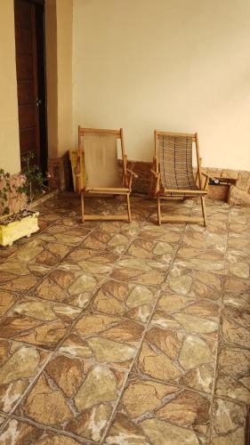 阿帕雷西达Casa Completa com 03 quartos a um quarteirão da Basílica Nacional的两把椅子坐在一间石地板的房间