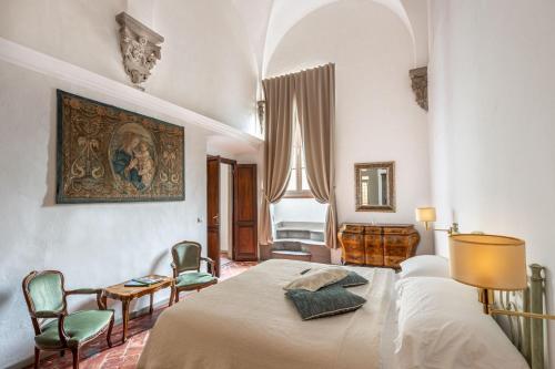 佛罗伦萨Palazzo Roselli Cecconi Apartments的卧室配有一张床和椅子,墙上挂有绘画作品
