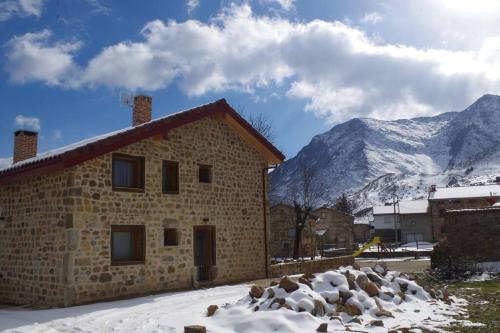 Besande42 Grados Norte Vadinia的一座石头建筑,背景是白雪 ⁇ 的山