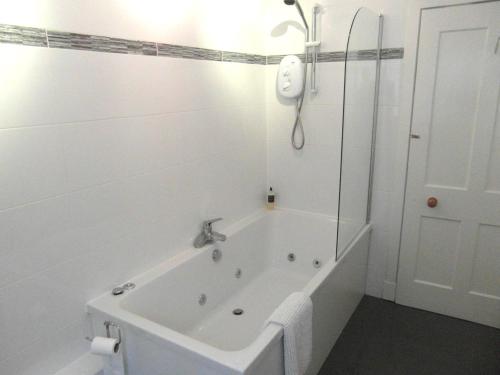 斯佩河畔格兰敦Amazing cottage with private indoor swim pool and hot tub的白色的浴室设有浴缸和淋浴。