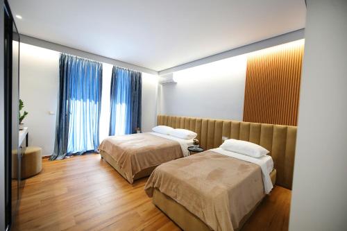 伏罗拉Ulcas guest huse的两张位于酒店客房的床,配有蓝色窗帘