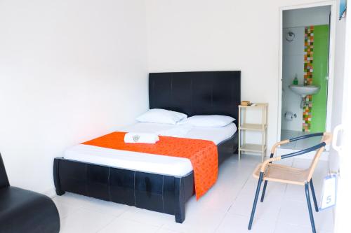 托卢Casa del Mar的一间卧室配有一张带橙色毯子和椅子的床