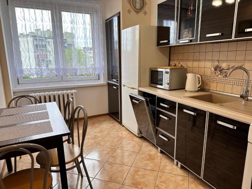 格利维采Apartament Dąbrowskiego - Gliwice的一间带桌子的厨房和一间带微波炉的厨房