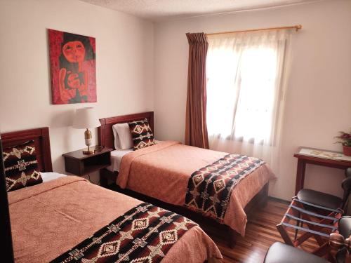基多Apartamento 32 Juana de Arco的酒店客房设有两张床和窗户。
