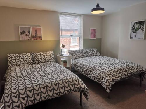 德比NEW Derby Pride Park Arena Moorways 4 bedrooms 7 beds -Spacious contractors or group -FREE PARKING的一间卧室设有两张床和窗户。