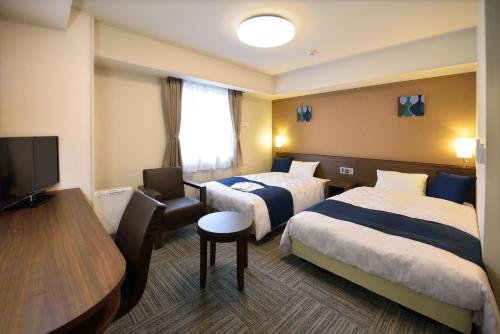 磐城Sunrise Inn Iwaki的酒店客房设有两张床和一台平面电视。