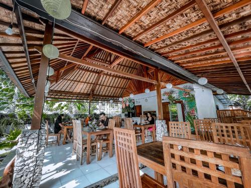 KlungkungMertha Sari Resto & Bungalow的餐厅设有桌椅和木制天花板。