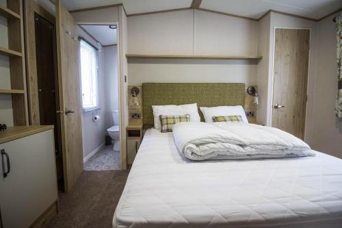 斯凯格内斯Beautiful 6 Berth Caravan With Decking At Southview Holiday Park Ref 33024o的一间带白色大床的卧室和一间浴室