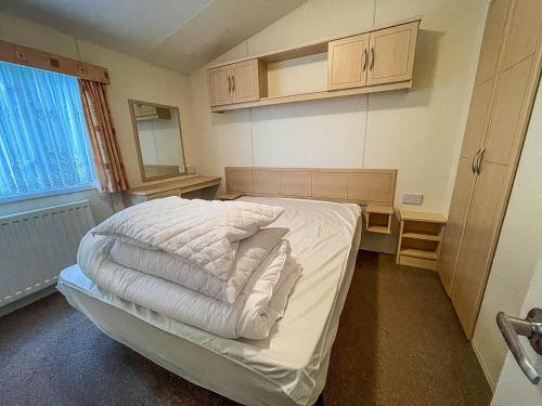 滨海克拉克顿Caravan At Highfield Grange With Decking, Sleeps 6 Ref 26446ba的一间小卧室,配有白色床单