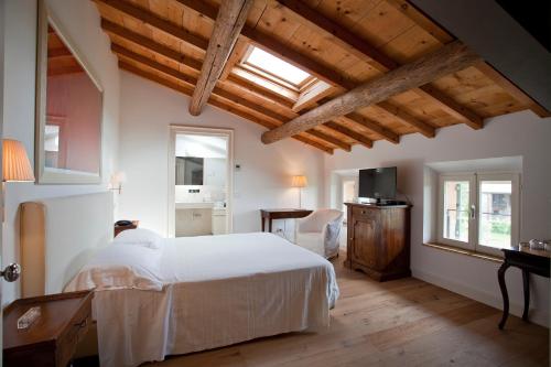 索纳Relais Corte Guastalla Apartments的卧室设有白色的床和木制天花板。
