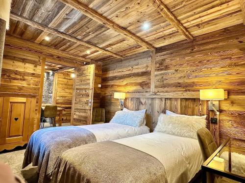 贝桑Chalet Les Cocales Résidence Séjour et nuitées B&B - Appartement Pin Cembro的木墙客房的两张床